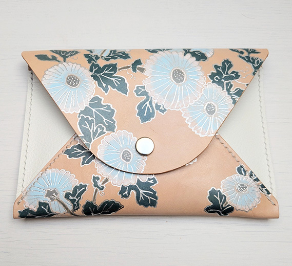 “Floral Pouch”, 2025 — envelope pouch in blush leather with daisies in pale blue foil and dark leaves